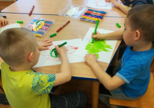 Dzieci przy stolikach rysują smoki.